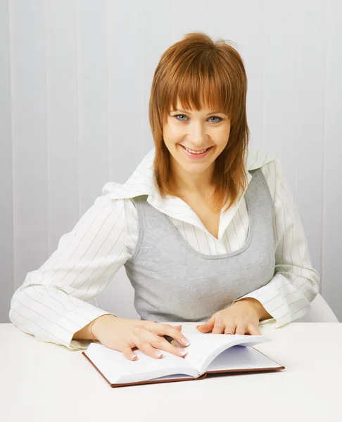 Menina atraente em uma blusa branca com um bloco de notas e caneta — Fotografia de Stock