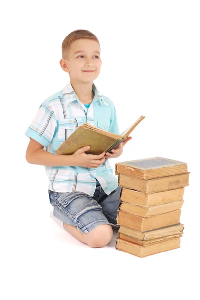Mladý chlapec sny v blízkosti otevřených staré knihy — Stock fotografie