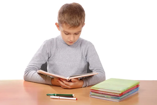 Chłopiec za stołem czyta książkę — Zdjęcie stockowe