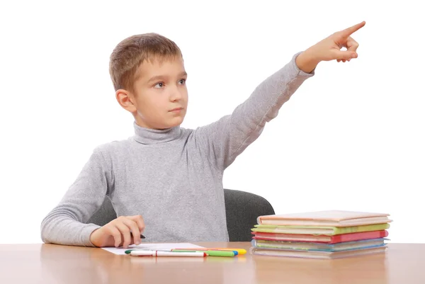 Boy sits at a table. boy shows a finger on a subject — Stock Photo, Image