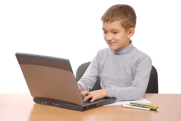 Schoolboy olhando para computador portátil no fundo branco — Fotografia de Stock
