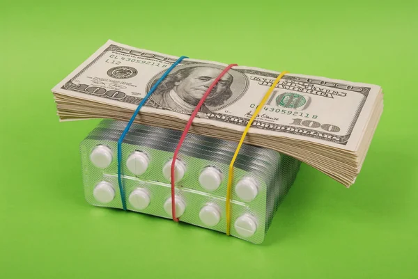 Paquete de dólares pone en el embalaje de comprimidos blancos — Foto de Stock