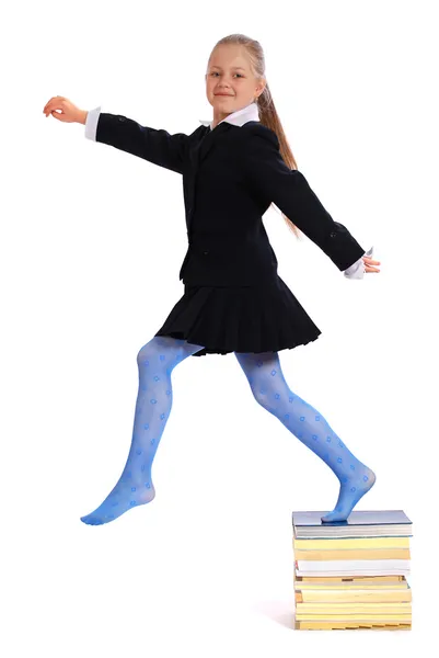 Girl jumps from a pile of books — Stock Photo, Image