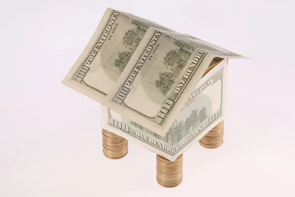 Дом из долларов стоит на монетах — стоковое фото