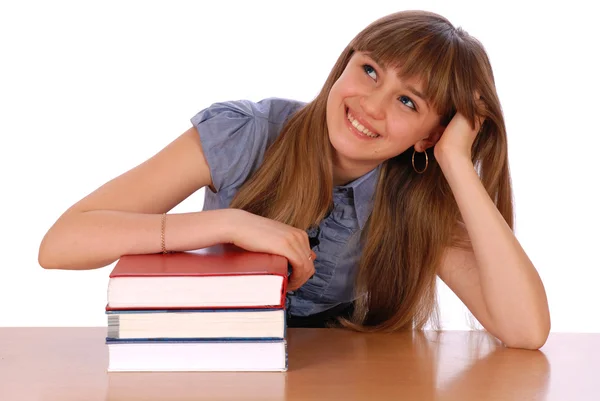 Dívka sedí u stolu a má dát ruku na hromadě knih — Stock fotografie