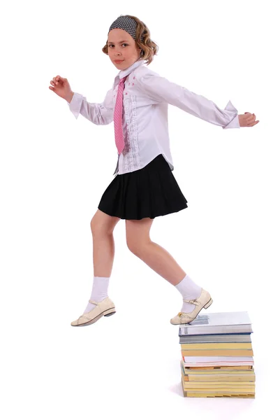 Flickan hoppar från en hög med böcker — Stockfoto