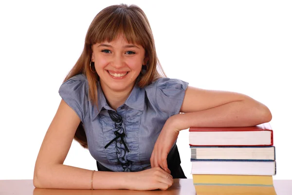 Dívka sedí u stolu a má dát ruku na hromadě knih — Stock fotografie