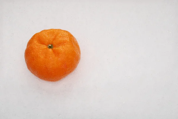 Апельсин лежит на снегу — стоковое фото