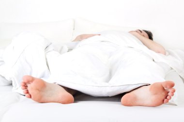 Sleeping man under a white blanket clipart