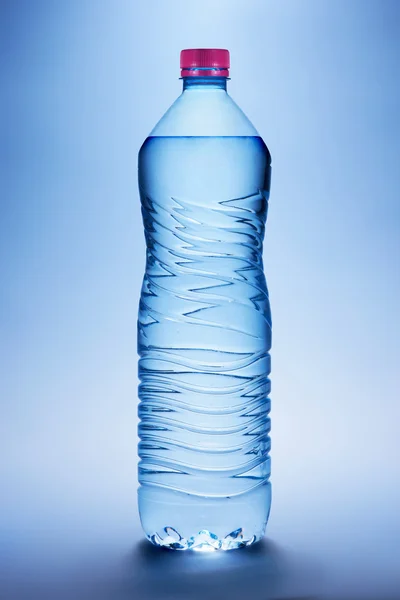 Bottiglia con acqua su fondo blu — Foto Stock