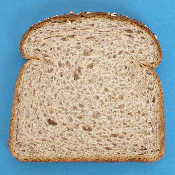 Sneetje volkoren brood op levendig blauw — Stockfoto