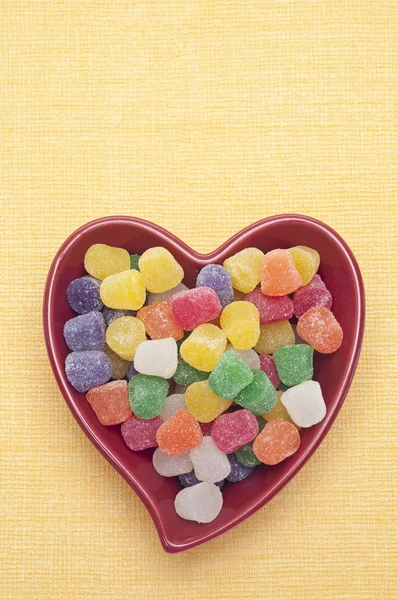 Słodycze przyprawy spada w czerwone serce w kształcie misy — Zdjęcie stockowe