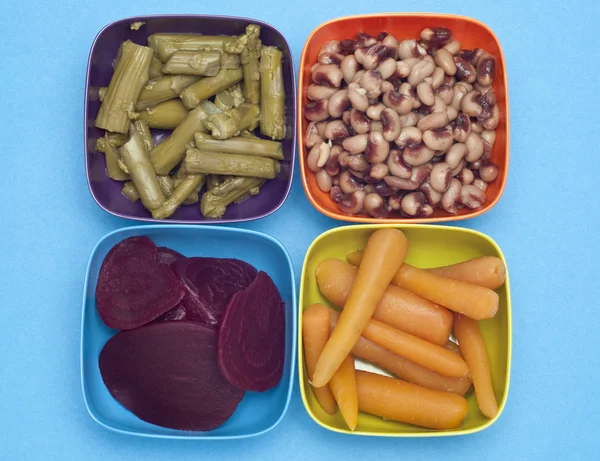 Morötter, rödbetor, sparris och black eyed peas i färgglada skålar. — Stockfoto