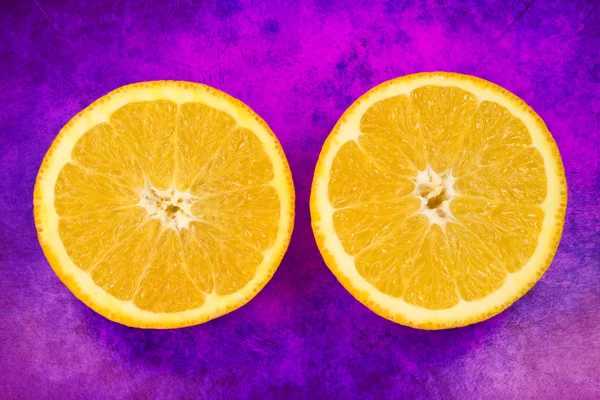 グランジ紫色の背景にオレンジ色の新鮮な果物の つの半分 — ストック写真