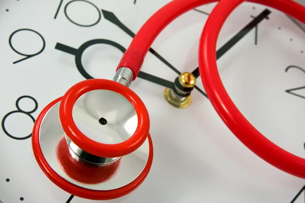 Red stethoscope on silver clock — Stock Photo, Image
