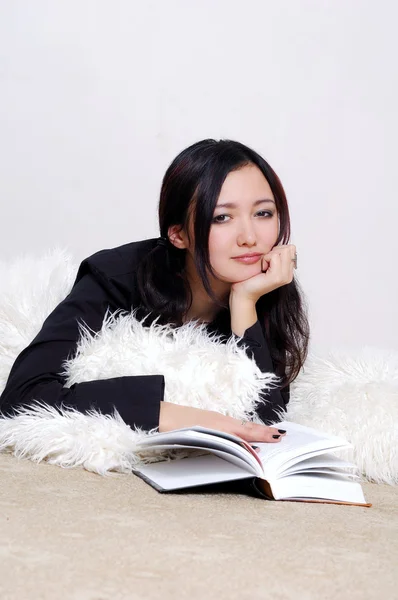 Beautiful Asian girl lying on the floor and reads a book — Stock Photo, Image