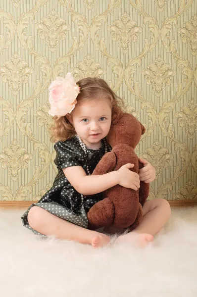 レトロ人形として服を着た小さな女の子がおもちゃで床に座ります — ストック写真