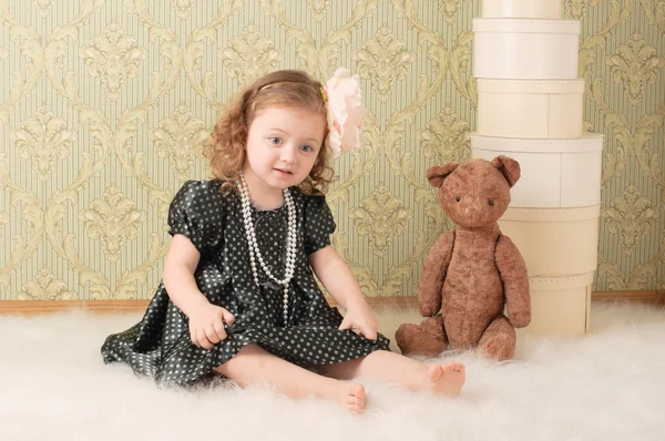 レトロ人形として服を着た小さな女の子がおもちゃで床に座ります — ストック写真