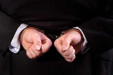 Close up of man wearing suit handcuffed behind his back. clipart
