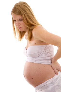 Pregnant woman bends over holding her back in pain. clipart