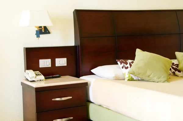 緑の枕と食器棚に電話でホテルのベッド — ストック写真