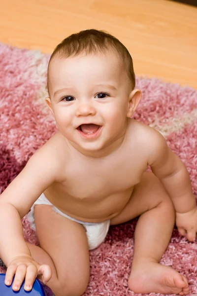 Smilende caucasain baby sidder på tæppet - Stock-foto