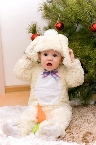 Pretty caucasian baby in rabbit costume near christmas tree — Stock Photo, Image