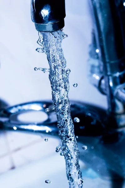 stock image Water running down from faucet in blue color