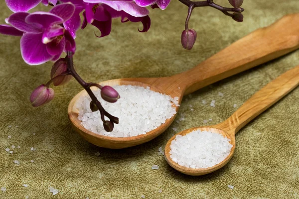 Spa essentials (bath salt in a spoon and flowers of orchids) — Stock Photo, Image