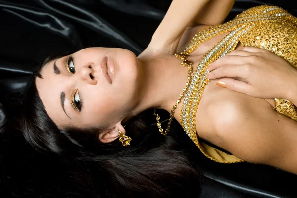 Mooie modieuze vrouw in gouden jurk — Stockfoto