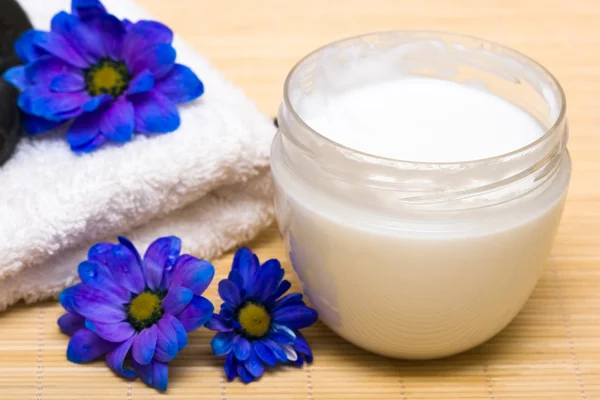 Spa essentials, crème en handdoek met blauwe bloemen — Stockfoto