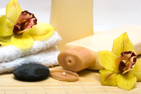 Bouteille jaune de shampooing avec serviette et orchidée — Photo