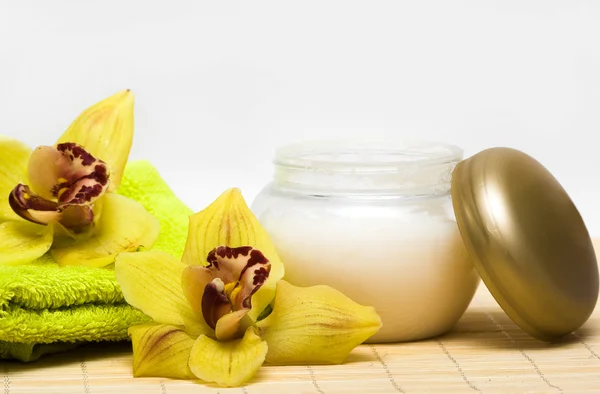 Esenciales de spa, crema y toalla con orquídeas amarillas — Foto de Stock