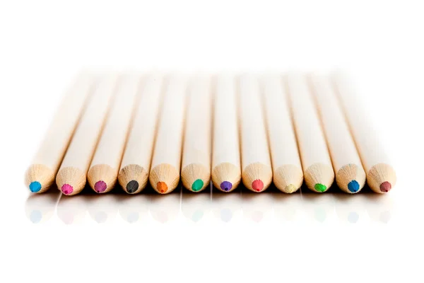 Många färgade pennor i rad över vit bakgrund — Stockfoto