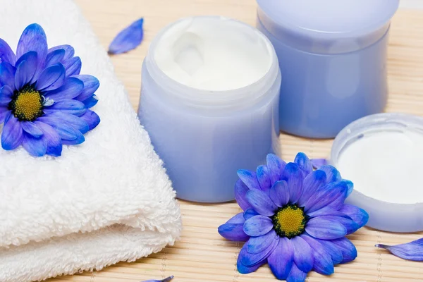 Spa essentials, cream and towel with blue flowers — Stock Photo, Image