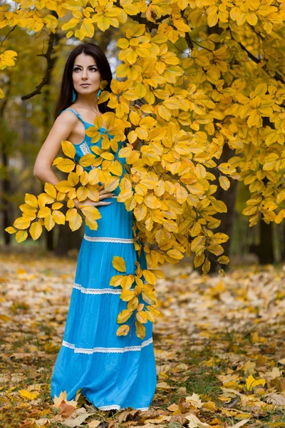 Mujer con hojas amarillas en otoño — Foto de Stock