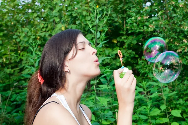 Young girl blowing soap bubbles in autumn park — Stock Photo, Image