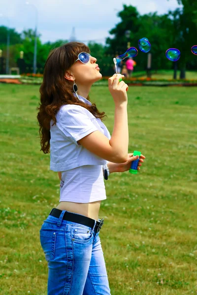 Jovem menina soprando bolhas de sabão no parque de outono — Fotografia de Stock