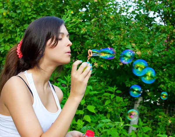 Молода дівчина дме мильні бульбашки в осінньому парку — стокове фото