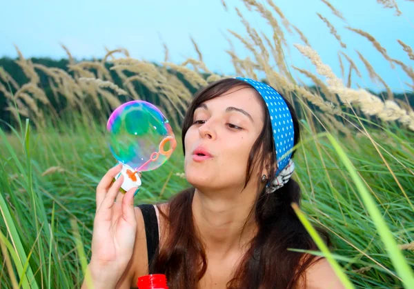 Young girl blowing soap bubbles in autumn park — Stock Photo, Image