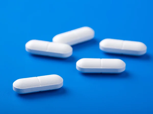Weiße Pillen über blaue — Stockfoto