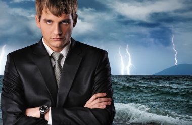 Seriour businessman over dark stormy sky clipart