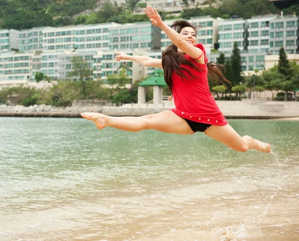 Beautiful young woman jumping in the sea — Stock Photo, Image