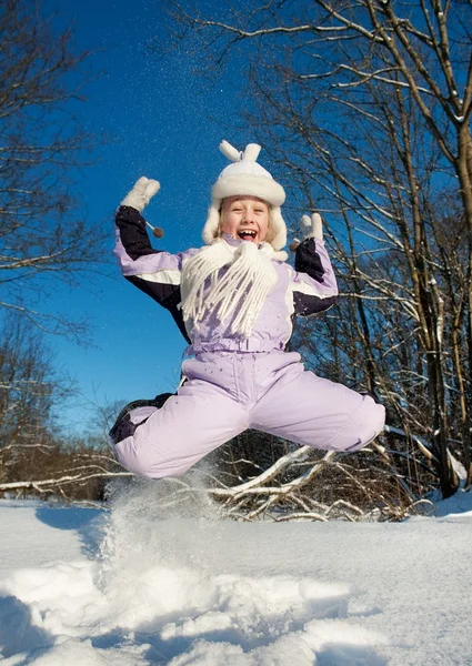 Menina feliz pulando na neve — Fotografia de Stock