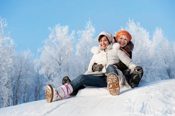 Mother and daughter sliding in the snow — Stockfoto