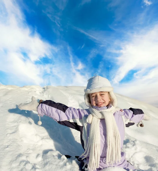 Glad liten flicka sitter i snöiga fältet — Stockfoto