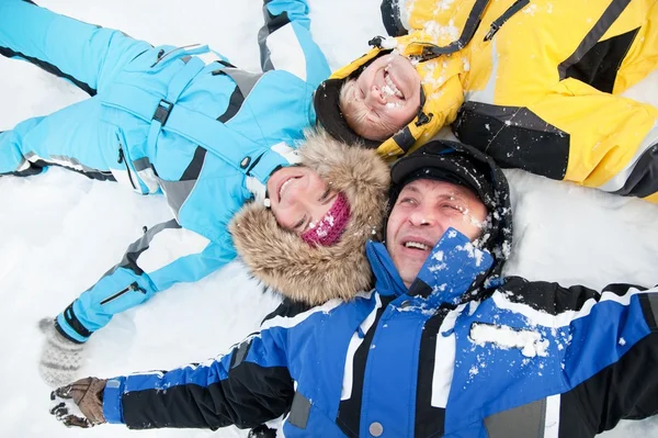 Famiglia felice sdraiata su una neve — Foto Stock
