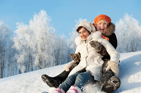 Mother and daughter sliding in the snow — Stockfoto