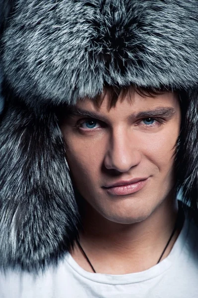 Portrait of handsome young man wearing fluffy hat — Stock Photo, Image