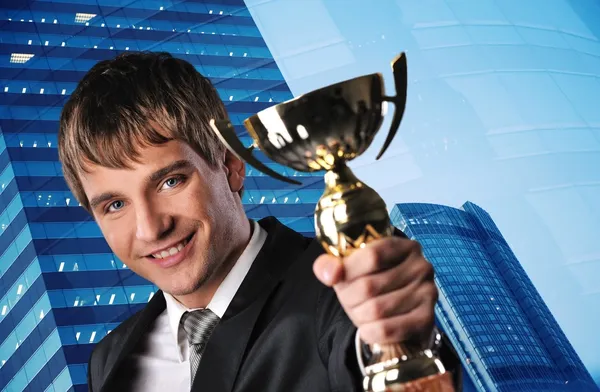 Šťastný podnikatel s zlatý pohár proti jeho kancelářská budova — Stock fotografie